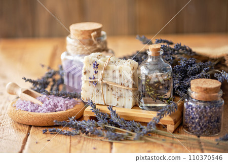Wellness treatments with lavender flowers on wooden table. Spa still-life. Essential oils, sea salt and handmade soap. Natural herb cosmetic with lavender flowers Wellness treatments with lavender flowers on wooden table. Spa still-life. Essential oils, sea salt and handmade soap. Natural herb cosmetic with lavender flowers 110370546
