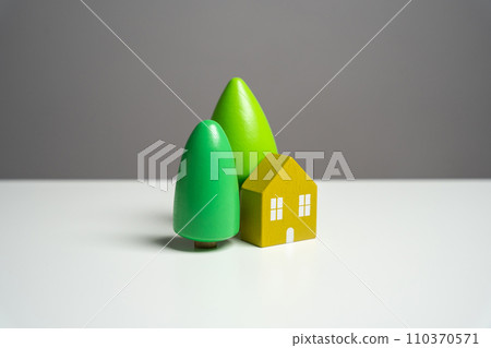 House with trees, figurine. Environmental friendliness and autonomy of housing. High energy saving technologies, in harmony with nature. Buying a nice house. Garden work, landscape design. 110370571