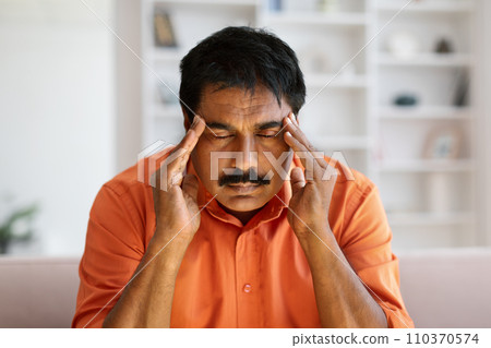 Closeup of mature indian man touching temples Closeup of mature indian man touching temples 110370574