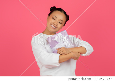 Smiling Young Asian Lady Hugging Wrapped Gift Box Smiling Young Asian Lady Hugging Wrapped Gift Box 110370732