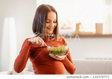 pregnant young woman eating healthy fresh salad at home 110370771
