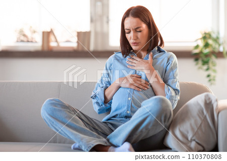 expecting mother gently touching her chest and stomach at home 110370808