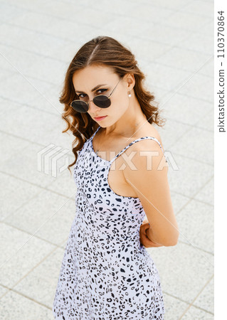 Cute woman put her hands behind her back and looks up 110370864