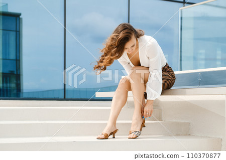 Woman fastening strap on her sandals Woman fastening strap on her sandals 110370877