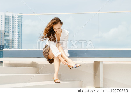 Woman fastening strap on her sandals Woman fastening strap on her sandals 110370883