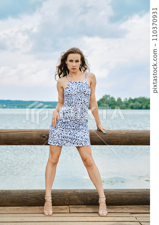 Stylish model posing in aggressive pose on shore of lake, looking intently at camera 110370931