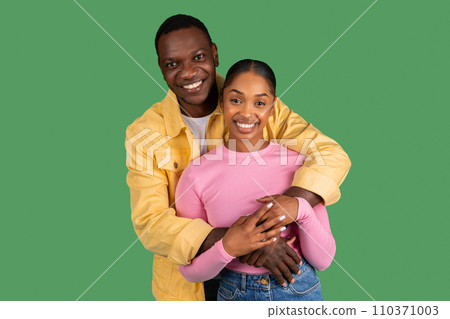Portrait of loving african american couple embracing on green background Portrait of loving african american couple embracing on green background 110371003