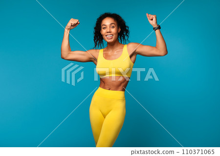 sporty black lady showing her biceps over blue studio background sporty black lady showing her biceps over blue studio background 110371065