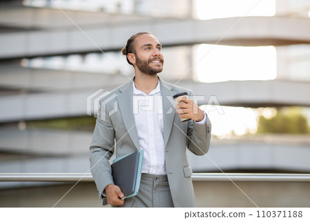 Relaxed young businessman enjoying coffee break while standing outdoors 110371188