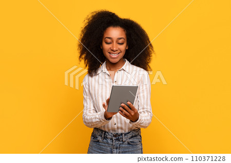 Smiling black woman using tablet, isolated on yellow background 110371228