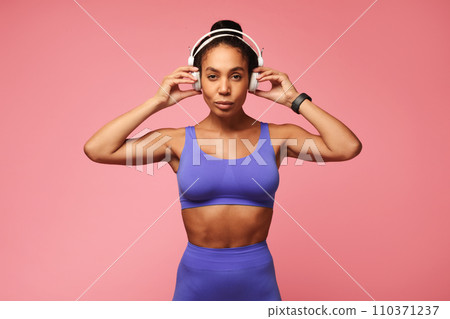 Athletic African American sportswoman in gym outfit wearing headphones, studio 110371237