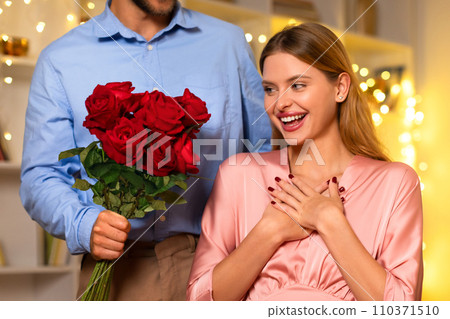 Overjoyed woman receiving red roses from a man, festive backdrop Overjoyed woman receiving red roses from a man, festive backdrop 110371510