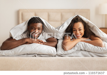 Happy Black Man And Woman Lying Under Blanket In Bed 110371637