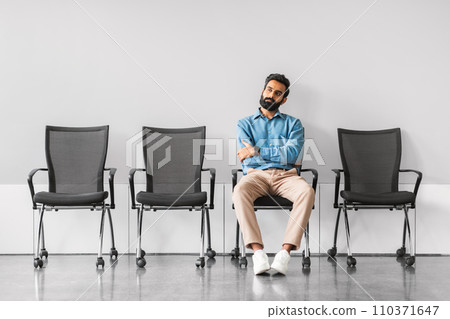 Professional indian man sitting with crossed arms in an empty meeting area 110371647