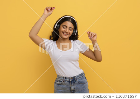 Joyful young pretty indian woman with headphones dancing Joyful young pretty indian woman with headphones dancing 110371657