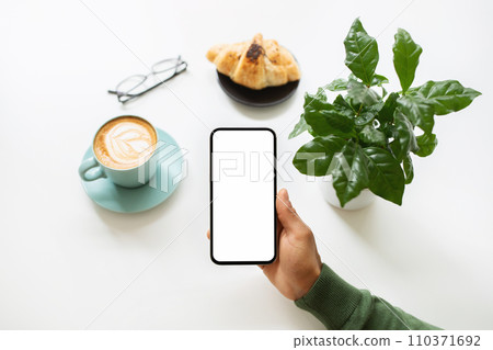 Black man hand holding phone, drinking coffee at cafe 110371692