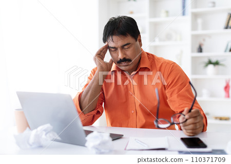 Tired middle aged indian man entrepreneur working at home office 110371709