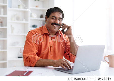 Middle aged eastern businessman talking on cellphone with client Middle aged eastern businessman talking on cellphone with client 110371716