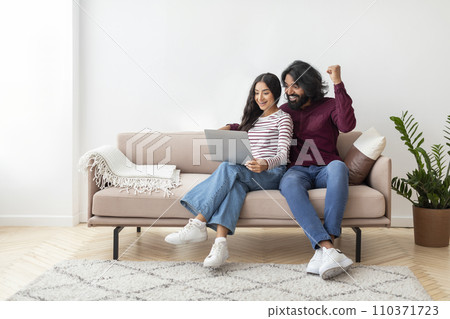 Happy millennial eastern couple using computer at home Happy millennial eastern couple using computer at home 110371723