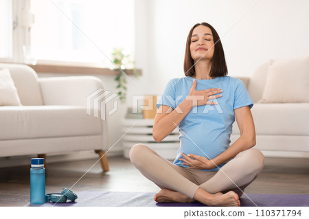 pregnant lady practicing yoga at home meditating focusing on breath 110371794