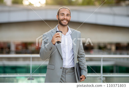 Confident male entrepreneur walking with coffee and laptop outdoors Confident male entrepreneur walking with coffee and laptop outdoors 110371803