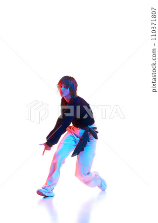 Young artistic woman in casual outfit dancing, performing hip hop isolated over white background in neon light 110371807