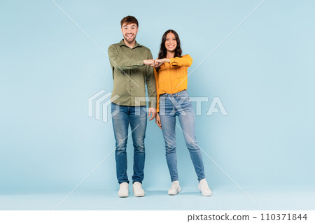 Man and woman fist bumping in casual wear on blue background 110371844