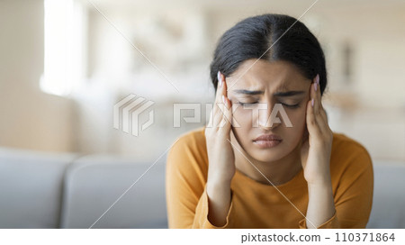 Stressed young indian woman suffering from severe headache or migraine at home Stressed young indian woman suffering from severe headache or migraine at home 110371864