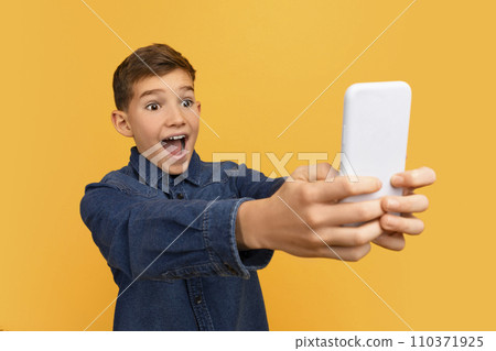 Cheerful Excited Teen Boy Looking At Smartphone Screen With Shock Cheerful Excited Teen Boy Looking At Smartphone Screen With Shock 110371925