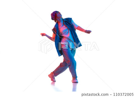 Stylish young girl in casual clothes in sport style dancing contemp, hip hop isolated over white background in neon light 110372005