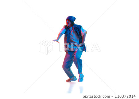Dynamic image of young girl in casual sportive cloths dancing hip hop isolated over white background in neon light Dynamic image of young girl in casual sportive cloths dancing hip hop isolated over white background in neon light 110372014