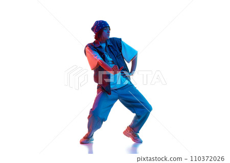 Dynamic image of young girl in casual sportive cloths dancing hip hop isolated over white background in neon light 110372026