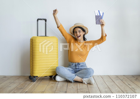 Joyful indian woman sitting on floor with her passport and boarding passes 110372107