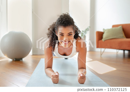 woman in activewear doing core strengthening plank exercise at home 110372125