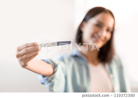 Happy young pregnant lady showing her positive pregnancy test indoor Happy young pregnant lady showing her positive pregnancy test indoor 110372380