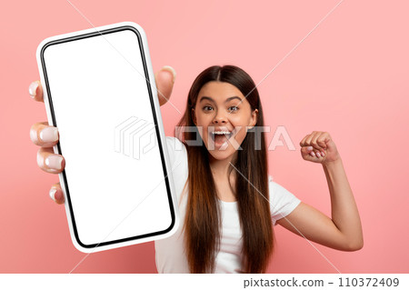 Overjoyed teen girl celebrating success, showing big phone 110372409