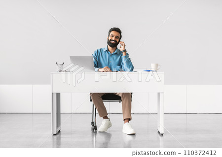 Relaxed businessman on a phone call at workdesk 110372412