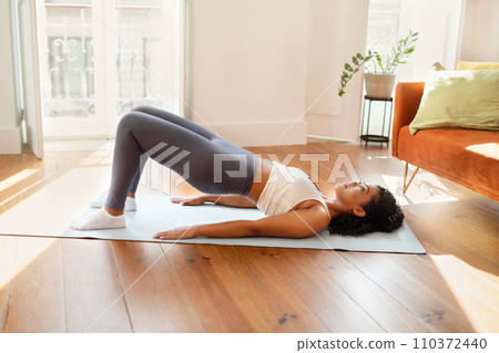 fit lady practicing yoga doing bridge pose on mat indoor 110372440