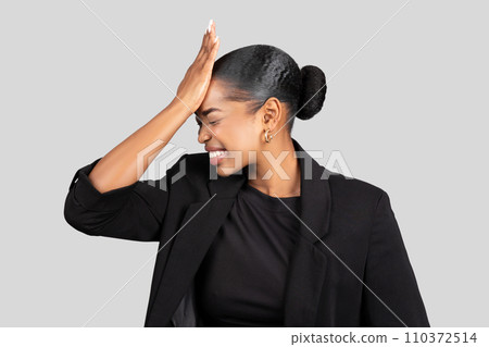 Sad young african american woman in formal suit put hand to forehead 110372514