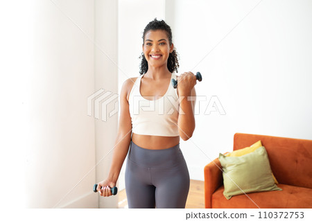 lady engages in workout with weights exercising holding dumbbells indoors 110372753