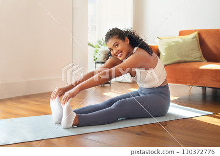 woman exercising doing seated toe touch in living room 110372776