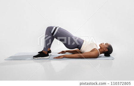African American Woman Doing Glute Bridge Exercise Over White Background 110372805