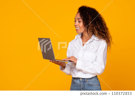 black woman holding and using laptop working online in studio 110372853