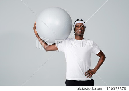Handsome sporty black man holding large gym ball over his head Handsome sporty black man holding large gym ball over his head 110372878