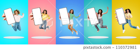 Happy Millennial Women With Blank Smartphones In Hands Jumping Over Colorful Backgrounds 110372981