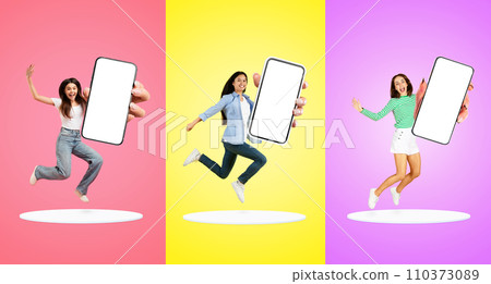 Joyful Young Women Jumping With Big Blank Smartphone In Hands Above Platforms Joyful Young Women Jumping With Big Blank Smartphone In Hands Above Platforms 110373089