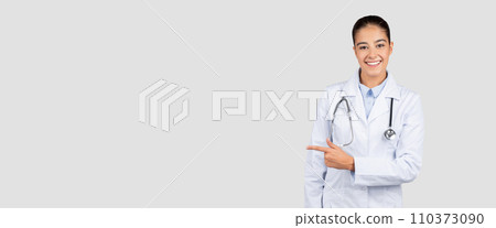 Radiant Caucasian millennial doctor with a stethoscope pointing to the side, suggesting a product or service Radiant Caucasian millennial doctor with a stethoscope pointing to the side, suggesting a product or service 110373090