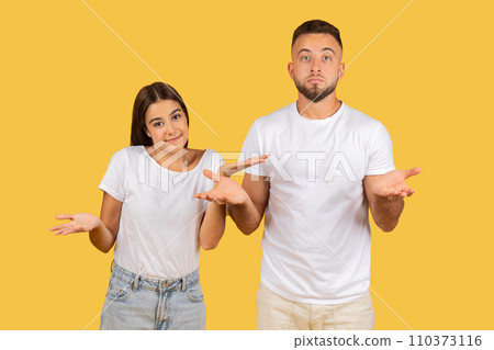 A young couple in white t-shirts shrugging with their palms up 110373116
