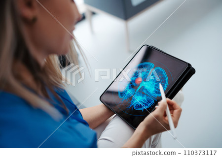 Portrait of female doctor sitting in office, looking at test results CT scans in tablet. Female surgeon in modern medical clinic. Portrait of female doctor sitting in office, looking at test results CT scans in tablet. Female surgeon in modern medical clinic. 110373117