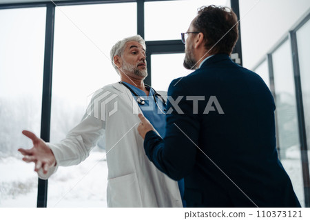 Violence against health workers. Patient is aggressive, have conflict with doctor in hospital corridor. Visitor holding doctor by coat, screaming, threatening him. 110373121